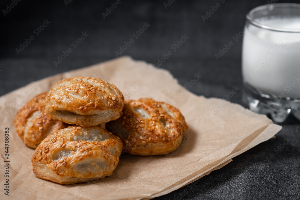 Buns from the Kraft oven, food paper and dairy products, a glass of milk.
Photo on a dark background.