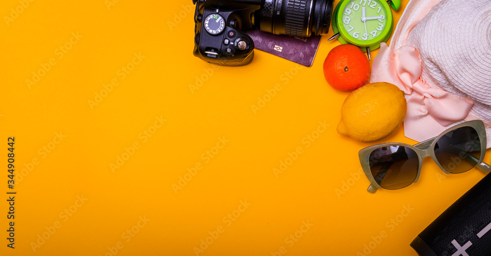 Best beach accessories on the yellow background: sunglasses, friuts, wireless speaker and striped hat. Summer is coming concept with copy space your text.