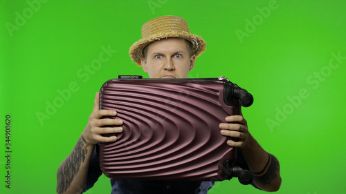 Portrait of man tourist hides behind a suitcase and looks out. Chroma key