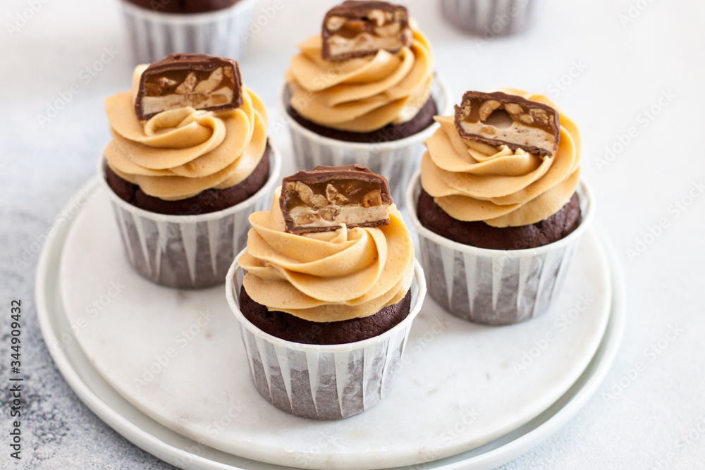 Homemade chocolate dough cupcakes with peanut butter frosting and snickers bites. Selective focus