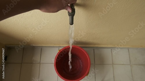 A top down footage of man open tap and water been filled in the bucket for floor cleaning.