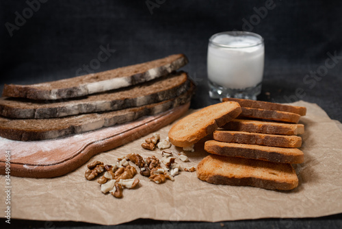 Baking, dark bread, cookies and rolls on a dark background.
Kraft paper. Milk in a transparent glass.