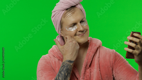Portrait of transsexual man in bathrobe making selfies using mobile phone