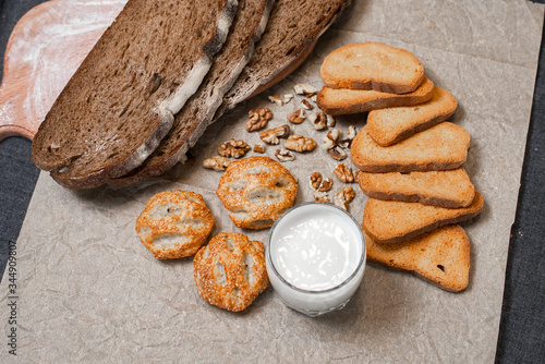 Baking, dark bread, cookies and rolls on a dark background.
Kraft paper. Milk in a transparent glass.