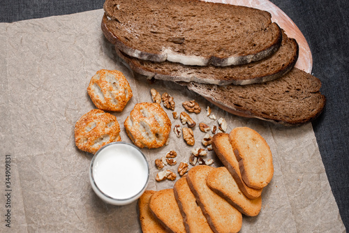 Baking, dark bread, cookies and rolls on a dark background.
Kraft paper. Milk in a transparent glass.