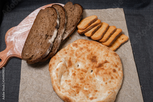 Baking, dark bread, cookies and rolls on a dark background.
Kraft paper. Milk in a transparent glass.