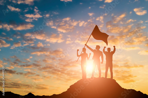 Silhouette of victory business team on mountain with sunset and sky background. Business teamwork success and leadership concept. photo