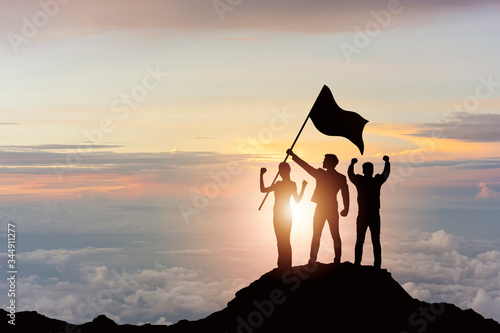 Silhouette of victory business team on mountain with sunset and sky background. Business teamwork success and leadership concept. photo
