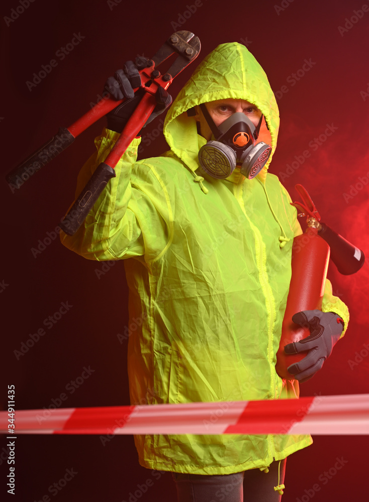 Fireman in respirator holding fire extinguisher and metal scissors Fireman in respirator holding fire extinguisher and metal scissors