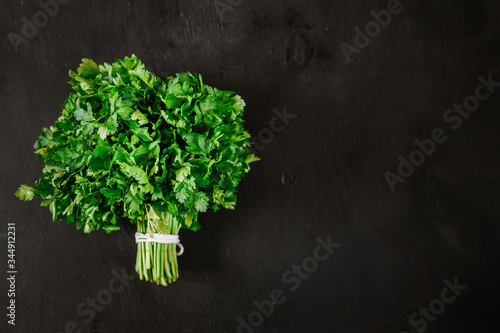 Bunch of fresh parsley on the black background. Top view. Copy space. Flatlay