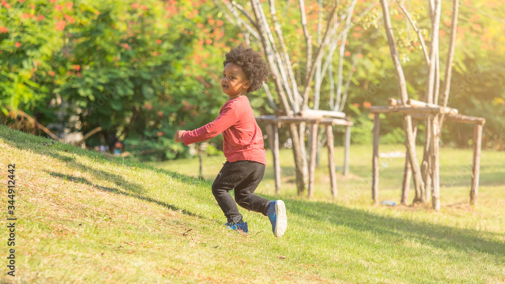 Little african boy running around happily in the park. Healthy lifestyle, children day
