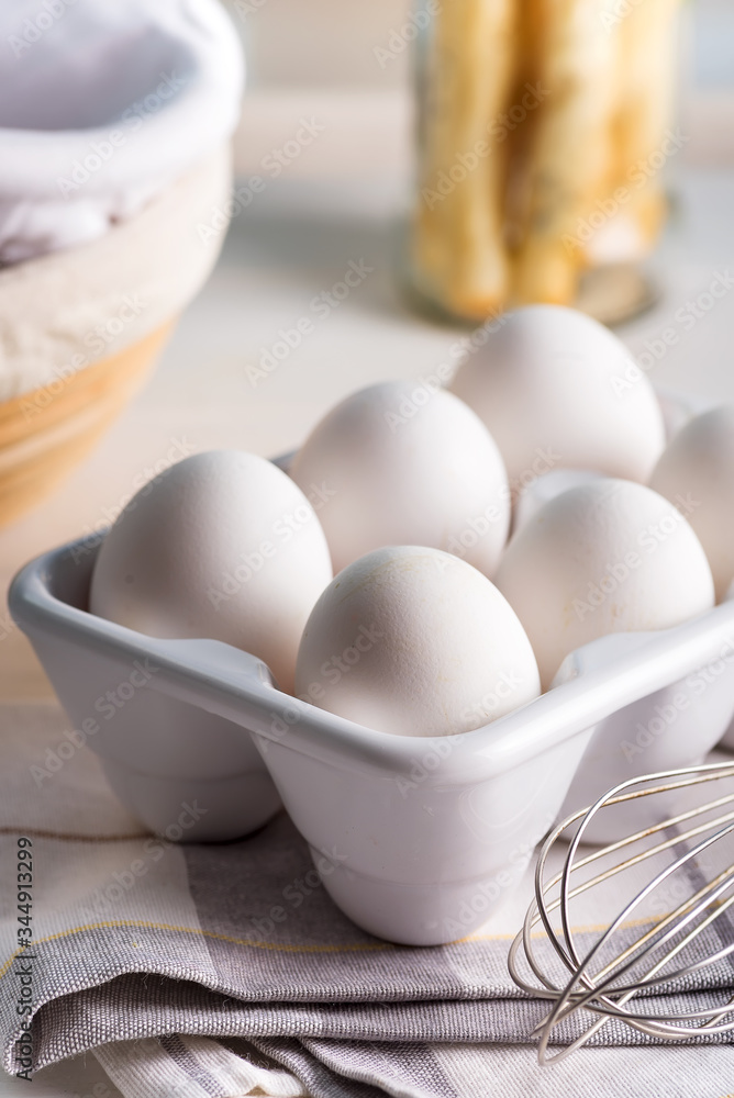 Ceramic container with natural organic farm eggs on a blurred kitchen background. Ceramic container with natural organic farm eggs on a blurred kitchen background.