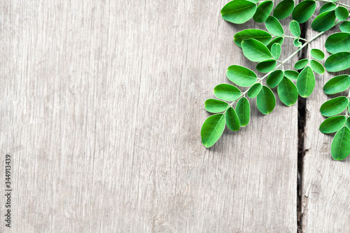 Closeup top view moringa leaves branch on wood background, herb and medical concept