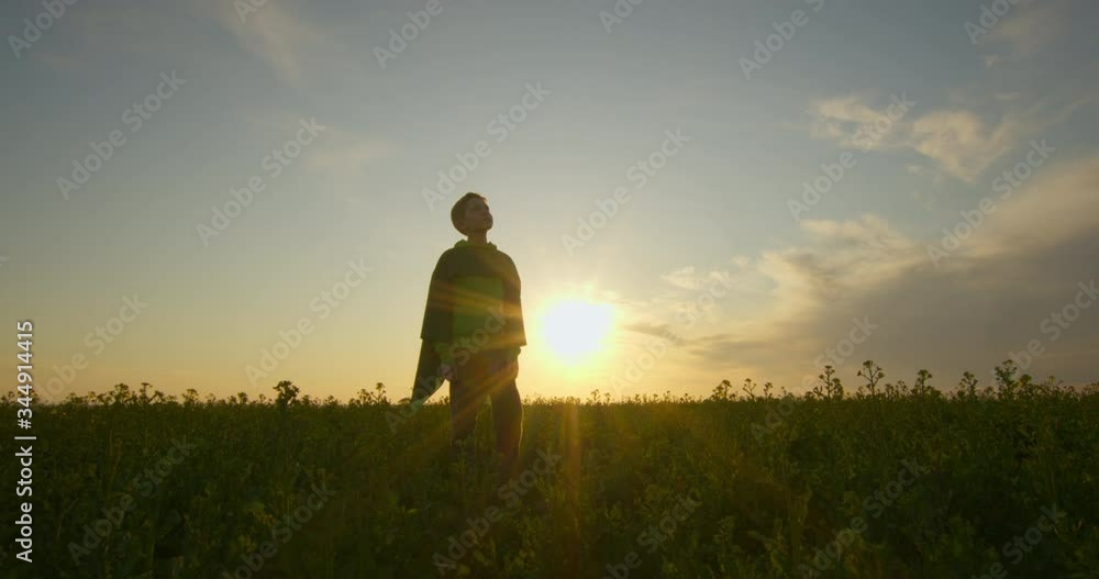 A boy-superhero is standing on the field. Sunset. 4K A boy-superhero is standing on the field. Sunset. 4K