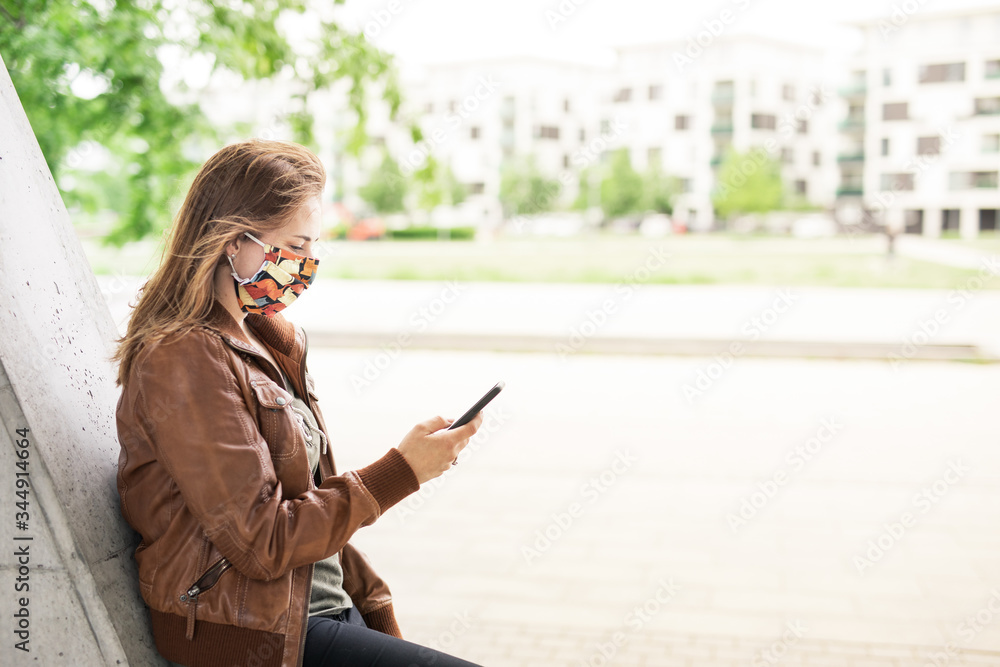 Fototapeta premium Frau mit Maske und Handy im Park