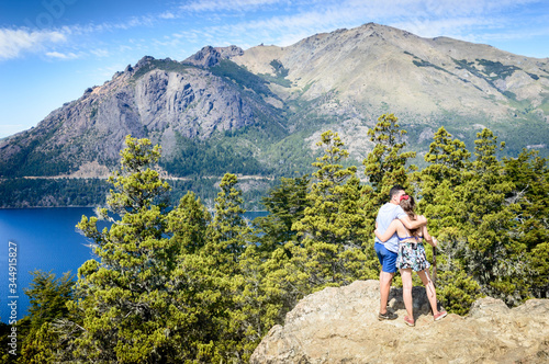 People in a mountain landscape in sunny day. Green pines and lake under the mountain in Bariloche.