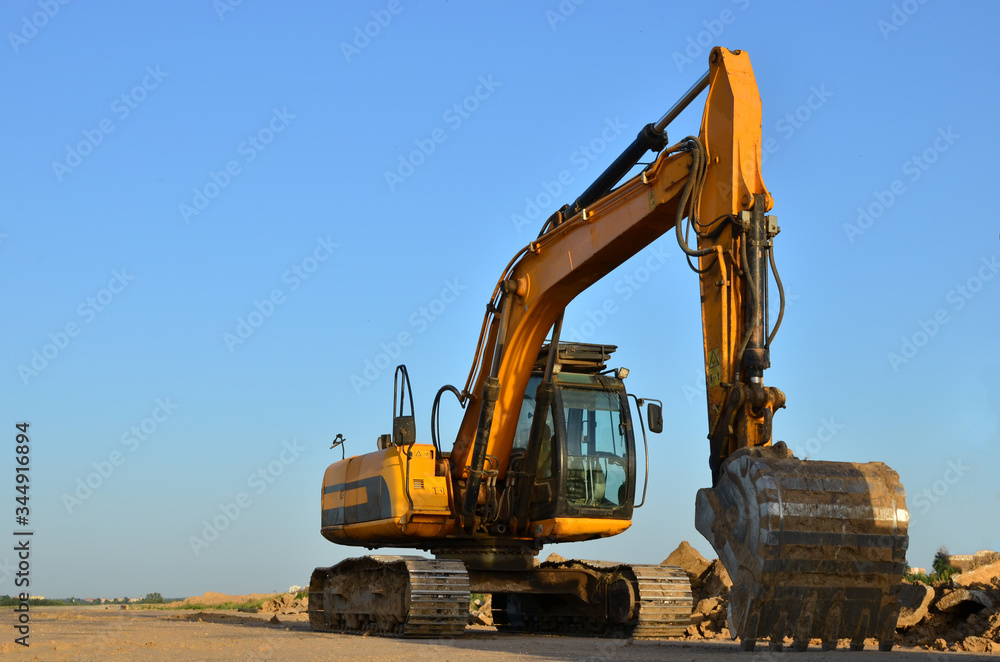 Excavator digs the ground for the foundation and construction of a new building. Road repair, asphalt replacement, renovating a section of a highway, laying or replacement of underground sewer pipes Excavator digs the ground for the foundation and construction of a new building. Road repair, asphalt replacement, renovating a section of a highway, laying or replacement of underground sewer pipes
