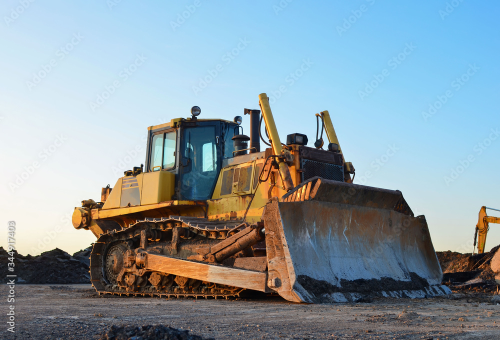 Dozer with bucket for pool excavation and utility trenching. Bulldozer during land clearing and foundation digging at construction site. Earth-moving equipment background Dozer with bucket for pool excavation and utility trenching. Bulldozer during land clearing and foundation digging at construction site. Earth-moving equipment background
