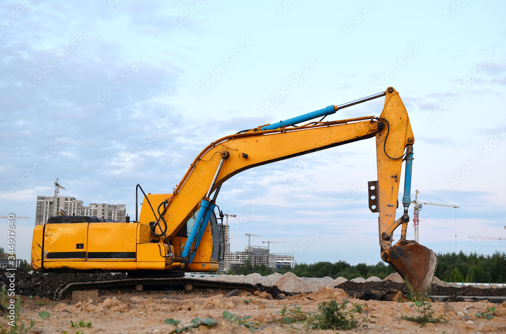 Excavator with a large iron bucket on a construction site during road works. Backhoe dig the ground for the foundation, laying storm sewer pipes. Installation of water main systems. Excavator with a large iron bucket on a construction site during road works. Backhoe dig the ground for the foundation, laying storm sewer pipes. Installation of water main systems.