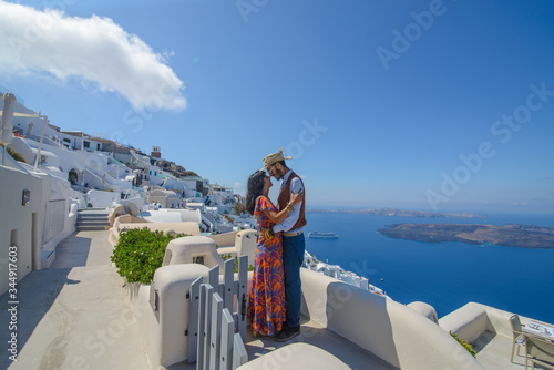 A man and a woman are hugging against the backdrop of Skaros Rock on Santorini Island. The village of Imerovigli..He is an ethnic gypsy. She is an Israeli.