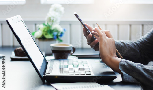 Close-up of businesswoman working at home with laptop and use smartphone to searching information online, Concept work from home