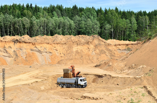 Excavator developing the sand on the opencast and loading it to the heavy dump truck. Processing of loose material in mining quarry. Drill, breaking, processing plant, crushing and screening