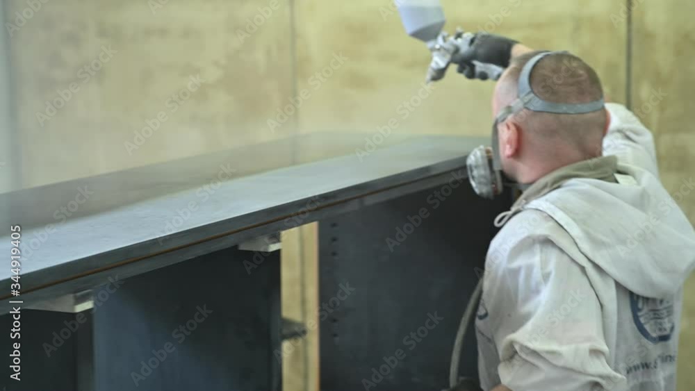 Man spraying varnish on a piece of furniture in a painting chamber Man spraying varnish on a piece of furniture in a painting chamber