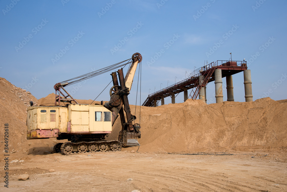 Huge mining excavator in the sand open-pit. Biggest digger working in quarry. Largest tracked machine with electric shovel. Heavy duty electric-powered mining equipment