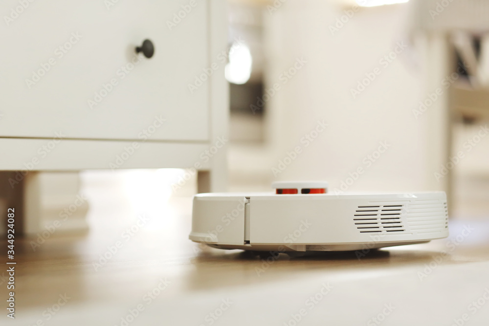 white robotic vacuum cleaner. The robot is controlled by voice commands for direct cleaning. Modern technology of smart cleaning. scheduled cleaning of the apartment. selective focus