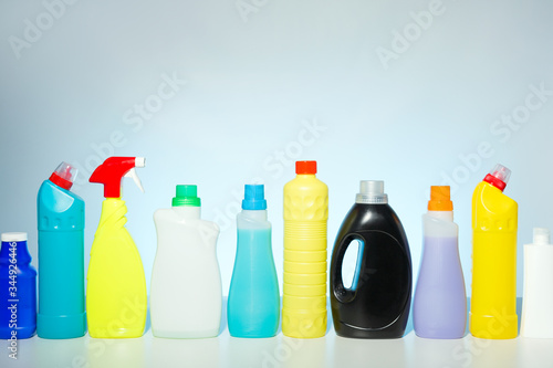 Row of colorful plastic detergent, soap bottles against a pale blue background