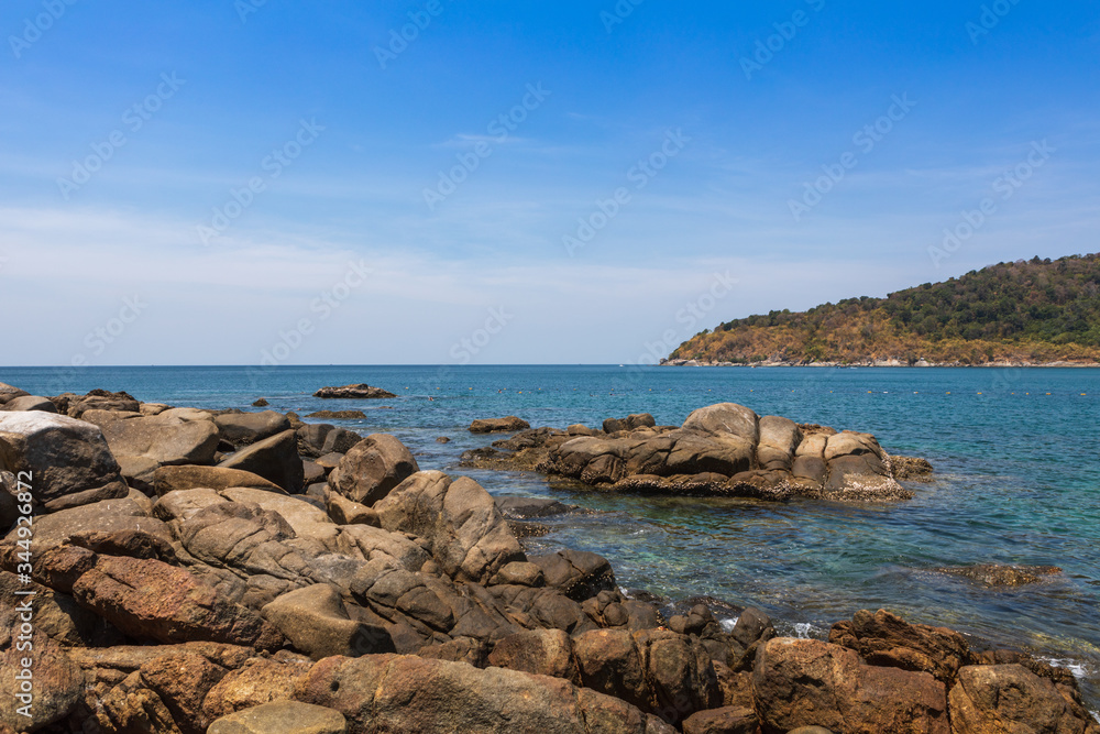 view from the rocky shore to the blue water on the island of Phuket Thailand