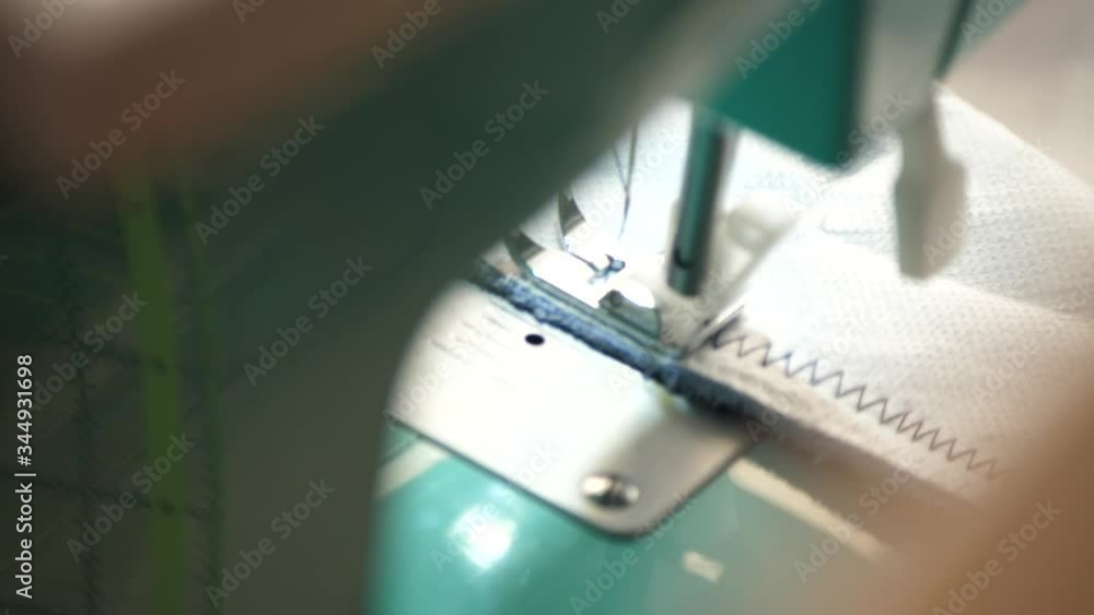 White material is fed through a sewing machine White material is fed through a sewing machine