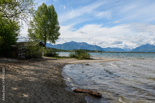 Chiemsee , Ufer im Frühjahr im Mai mit Bäumen udn Bergen, Himmel und Wolken photo