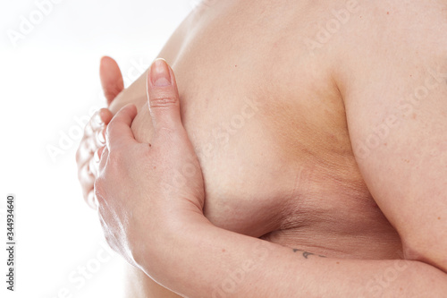 A 40-year-old overweight woman covers her sagging Breasts with her hands on a white isolated background. concept for medicine and cosmetology photo