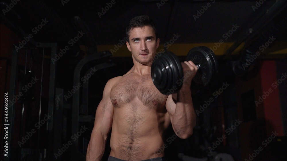 The athlete does a bench press with dumbbells while standing. Dumbbell Biceps Exercise The athlete does a bench press with dumbbells while standing. Dumbbell Biceps Exercise