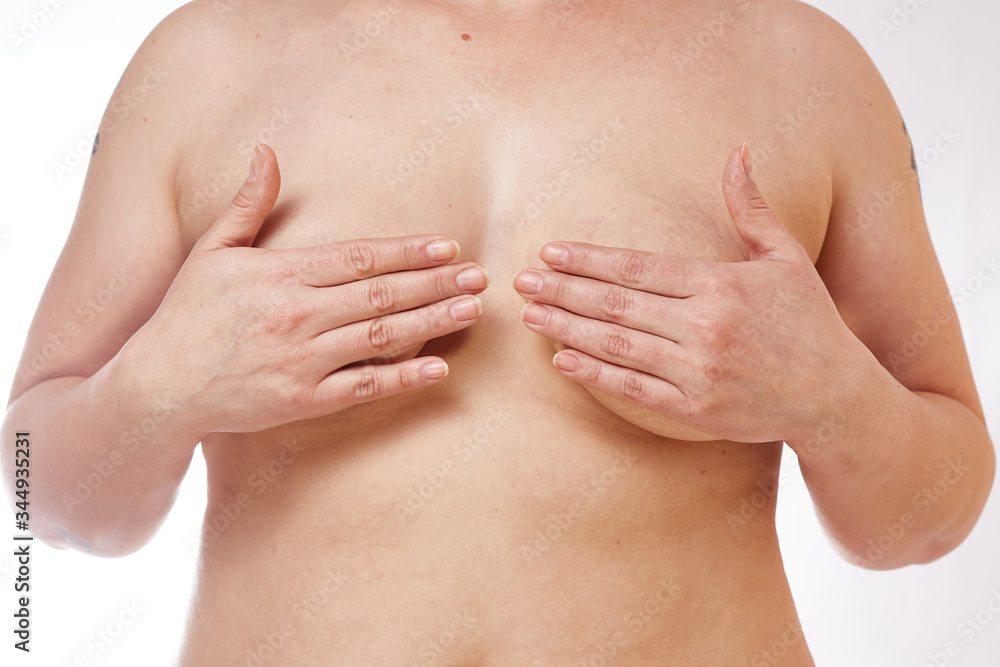 A 40-year-old overweight woman covers her sagging Breasts with her hands on  a white isolated background. concept for medicine and cosmetology Stock  Photo