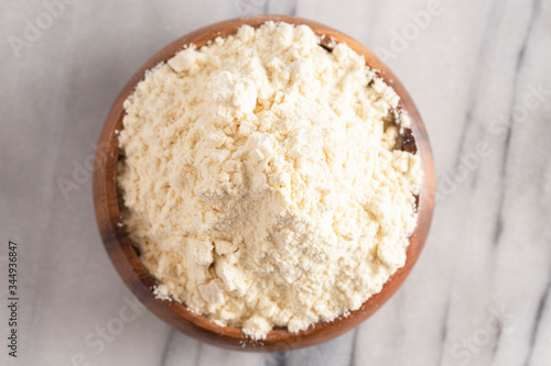 Bowl of Millet Flour in a Wood Bowl on a White Marble Countertop