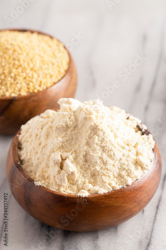 Whole Millet and Millet Flour in a Wood Bowl on a White Marble Countertop photo