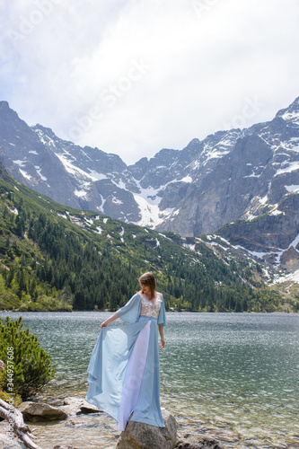 Portrait of a young woman on the background of the Polish lake "Sea Eye" in the Tatra Mountains. Portrait photography in the background of a quiet place without people.