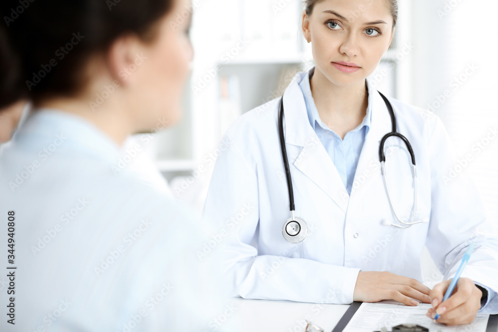 Doctor and patient are communicating while sitting at the table Doctor and patient are communicating while sitting at the table