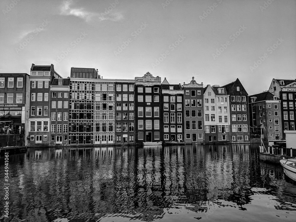 Black and White Photography of Traditional old buildings reflected on the canal's waters in Amsterdam, the Netherlands