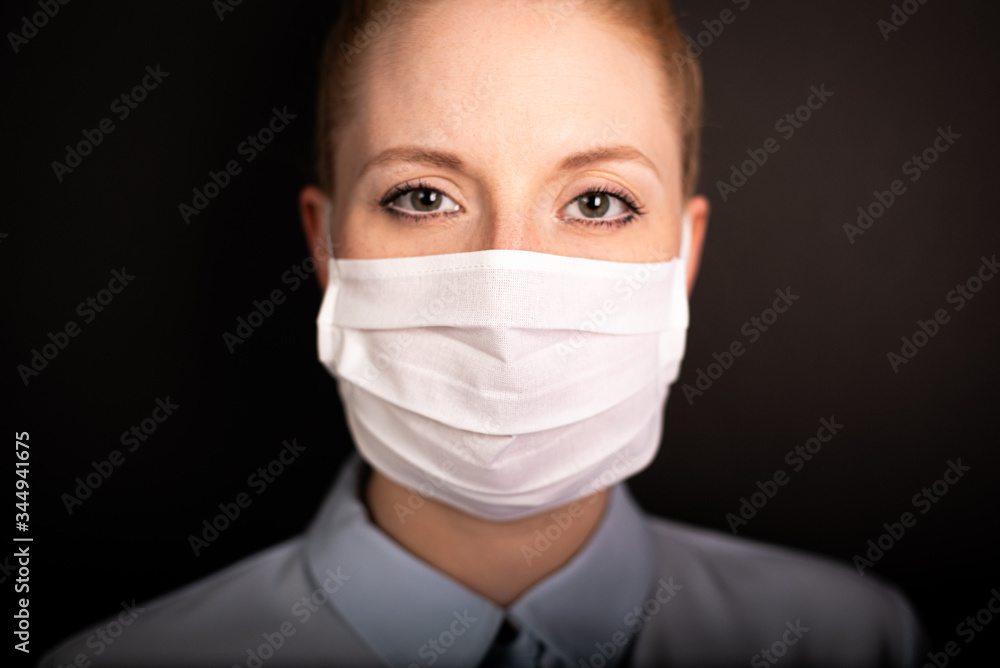 Junge Frau trägt Schutzmaske während Maskenpflicht vor schwarzen Hintergrund Junge Frau trägt Schutzmaske während Maskenpflicht vor schwarzen Hintergrund