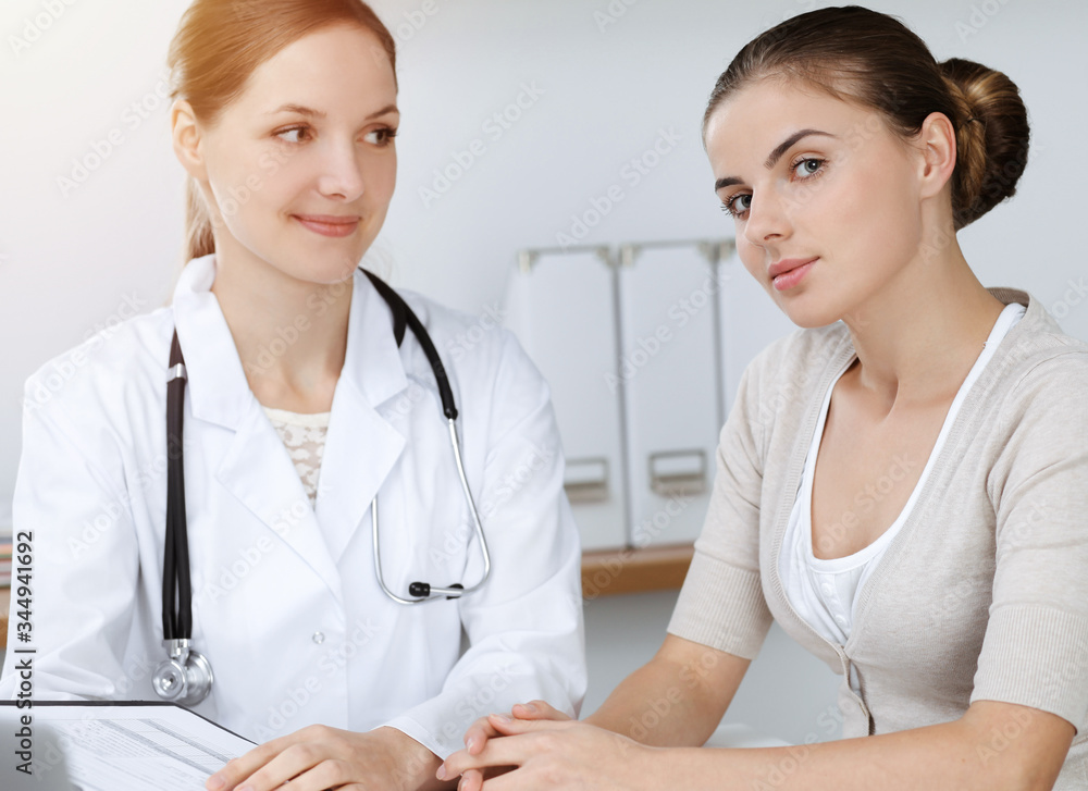Doctor and patient sitting and discussing health examination results in sunny clinic Doctor and patient sitting and discussing health examination results in sunny clinic