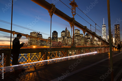 Man in New York City - sunset over Manhattan from Brooklyn Bridge.