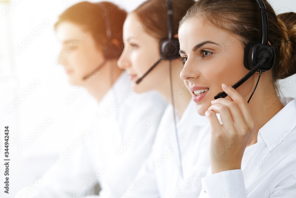 Call center. Beautiful young woman using headset and computer to help customers in sunny office. Business concept Call center. Beautiful young woman using headset and computer to help customers in sunny office. Business concept