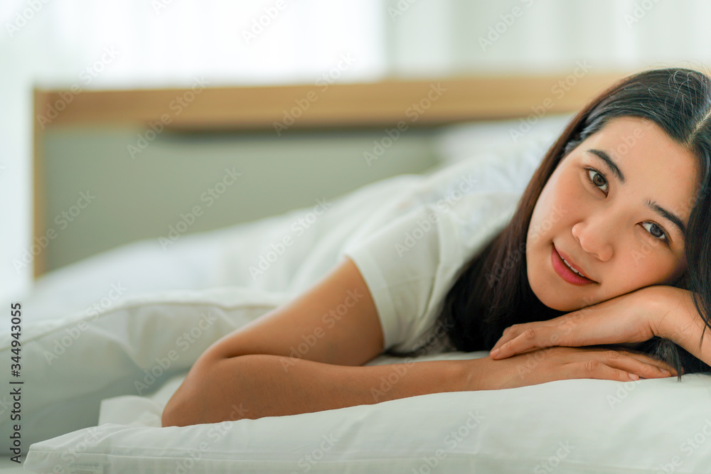 young asian woman lying on the bed under the clean white quilt both hands under the head resting stay home self quarantine during the covid-19 norona virus pandemic for social distancing young asian woman lying on the bed under the clean white quilt both hands under the head resting stay home self quarantine during the covid-19 norona virus pandemic for social distancing