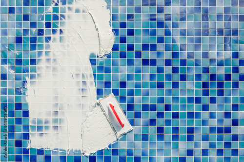 repairing and service of the pool. grouting tiles in the pool. Applying gap filling adhesive sealant or grout with a plastering trowel to the tiles in a swimming pool. photo
