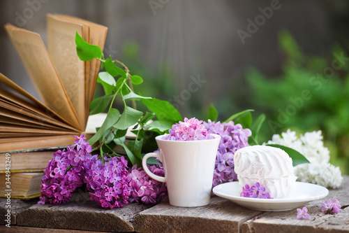 Cup of tea with lilac flowers on wooden background. Spring time. Vase with lilac. Copy space for text. The concept of holidays and good morning wishes.