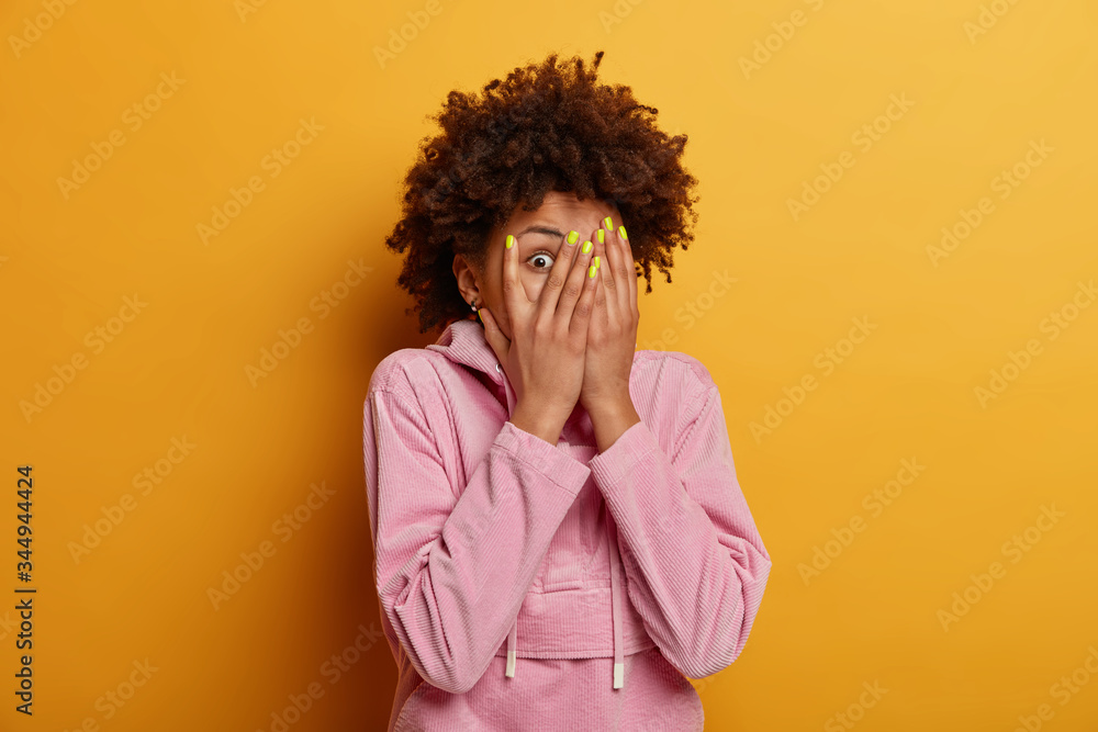 Ταπετσαρία Intrigued curious dark skinned woman peeks through fingers, covers face with pal