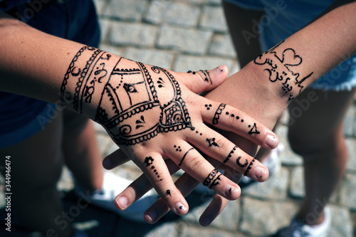 Tattooing with henna on the hands of two western girls.